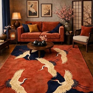 Peut inclure: Tapis de sol de couleur rouille avec un motif de grues crème en vol, sur un fond bleu foncé et rouille. Le tapis est dans un salon avec un canapé rouille, des meubles en bois et des œuvres d'art.