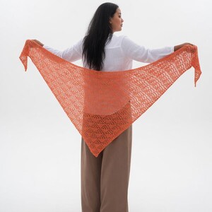 Peut inclure: Un châle triangulaire orange avec un motif ajouré délicat. Le châle est présenté ouvert, mettant en valeur son design et sa couleur. Le châle est fait d'un matériau léger, parfait pour être superposé.