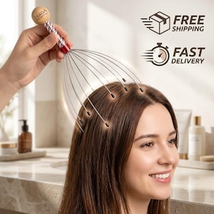 Puede incluir: Un masajeador de cuero cabelludo manual con mango de madera clara con el texto TRAQA PROFESSIONAL, un cuello en espiral metálico rojo y plateado, y múltiples alambres metálicos finos y flexibles que terminan en pequeñas puntas negras redondeadas.