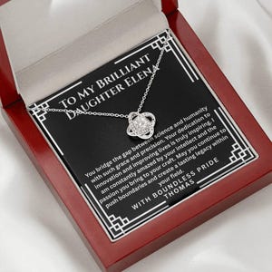 May include: A silver-toned necklace with a central knot-shaped pendant featuring a clear stone, presented in a mahogany-colored box. The card inside reads: TO MY BRILLIANT DAUGHTER ELENA, followed by a message about science, humanity, and legacy.