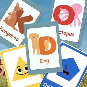 May include: A set of five educational flashcards featuring illustrations and text. Cards display a brown kangaroo with the letter K, a pink octopus with the letter O, a tan dog with the letter D, a yellow triangle, and a blue pentagon with faces.
