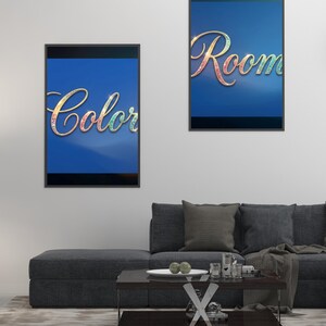 May include: Two framed art prints with the words "Color" and "Room" in a decorative font. The words have a colorful, iridescent effect against a blue background. The prints are displayed above a gray sofa.
