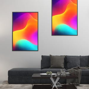 May include: Two framed abstract art prints with vibrant colors of purple, yellow, orange, and teal. The artwork features flowing, wave-like shapes. The prints are displayed above a dark gray sofa in a modern living room setting.