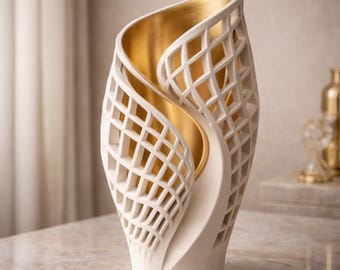 May include: A decorative white vase with a lattice design and a gold interior. The vase has a unique, flowing shape and is displayed on a marble surface. The gold interior adds a touch of elegance to the piece.