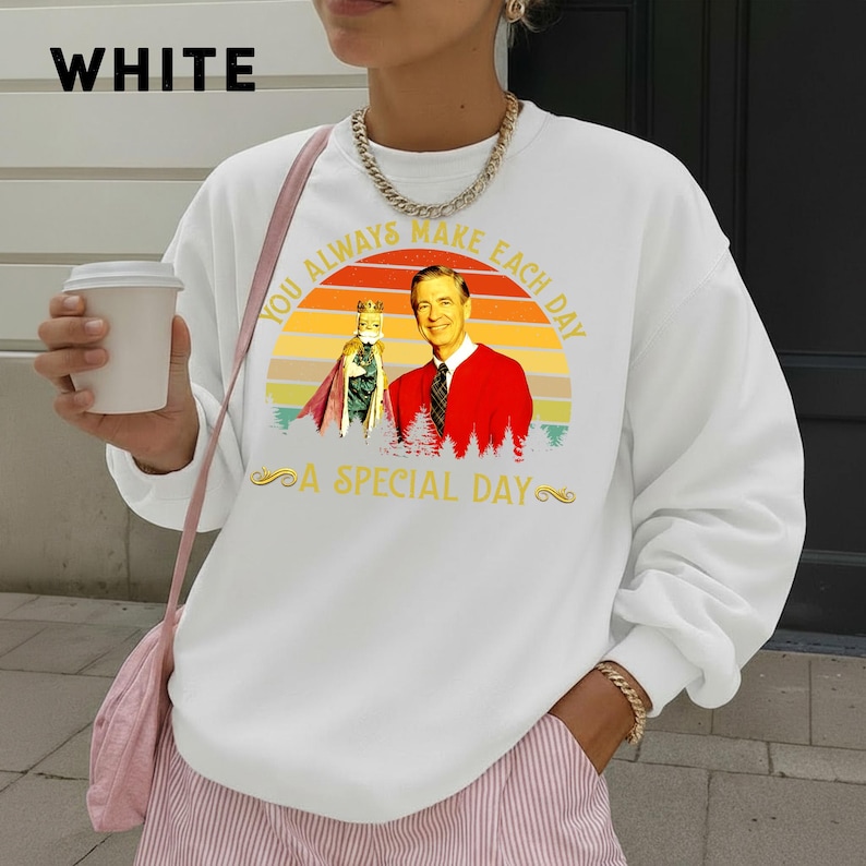 May include: White sweatshirt with the text "WHITE" at the top left. The sweatshirt features a graphic of a man in a red jacket and a figure in a cape, with the text "YOU ALWAYS MAKE EACH DAY A SPECIAL DAY".