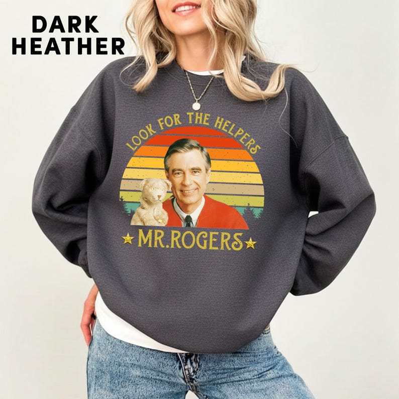May include: Dark heather gray sweatshirt featuring a graphic of Mr. Rogers with a puppet and the text "Look for the Helpers" and "Mr. Rogers" in a retro design. The sweatshirt has long sleeves.