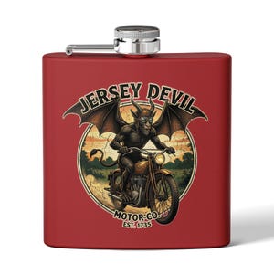 May include: A red stainless steel hip flask with a silver cap. The flask has a circular graphic of the Jersey Devil riding a motorcycle, with the text "Jersey Devil Motor Co. Est. 1735".