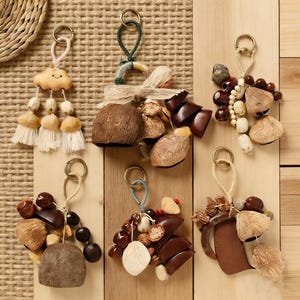 以下が含まれることがあります： 黒い持ち手と「But First, Coffee」のテキストが黒い太字で書かれた白いセラミックマグ。マグカップはぼやけた背景に置かれており、居心地の良い環境を示唆しています。