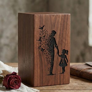 May include: A wooden urn with a dark brown finish. The front features a black etched design of a parent holding a child's hand, with the parent's form dissolving into butterflies. Birds are also etched above the figures.