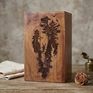 May include: A wooden box with a carved design of a person walking through a forest, with a deer and birds. The box is rectangular and made of a light brown wood.