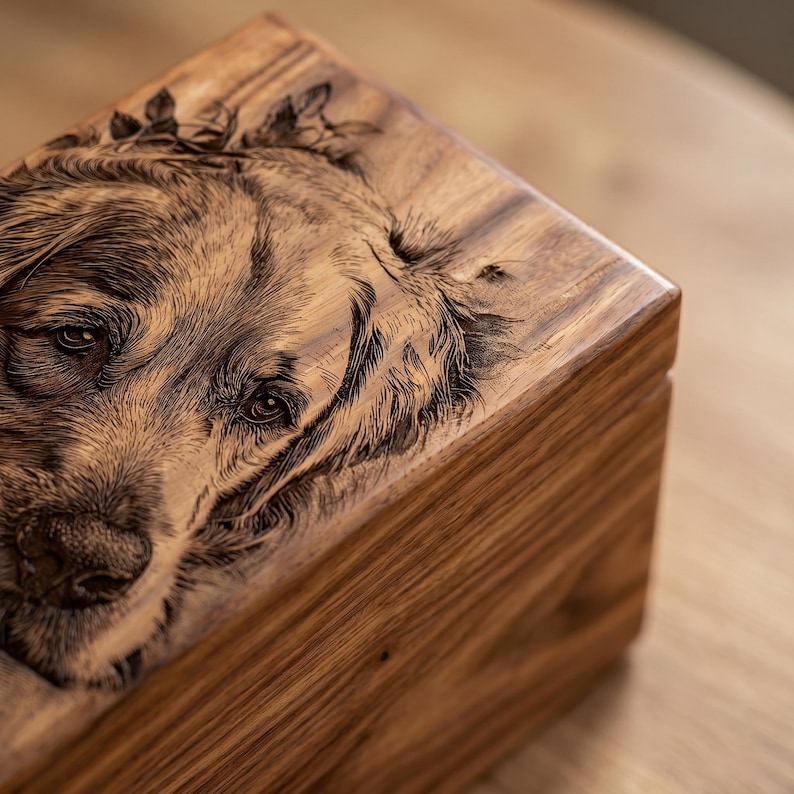 May include: A rectangular wooden box featuring a detailed laser-engraved portrait of a golden retriever on the lid. The natural wood grain is visible across the surface, and the engraving captures the dog's facial features and fur texture.