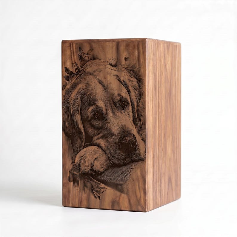 May include: A rectangular wooden urn featuring a detailed laser-engraved portrait of a golden retriever dog resting its head on its paws. The natural wood grain is visible across the surface, with dark brown etched lines defining the dog's features.