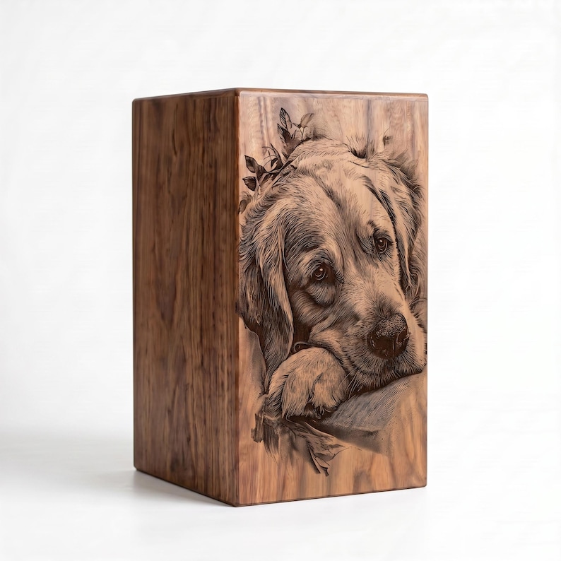 May include: A rectangular wooden urn featuring a detailed, dark brown laser-engraved portrait of a golden retriever dog resting its head on its paws. The natural wood grain is visible across the surface, showcasing light and dark brown tones.