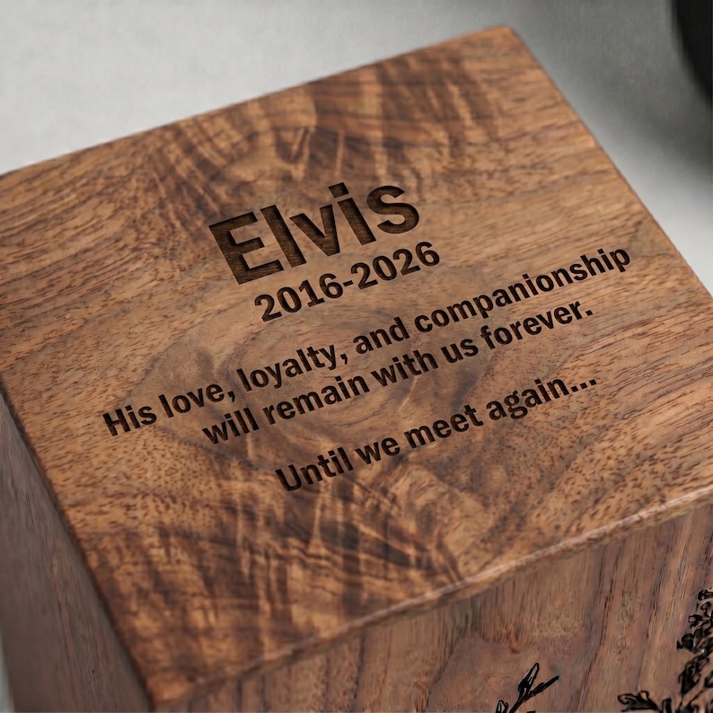Puede incluir: Una caja cuadrada de madera con un acabado de veta de madera marr&oacute;n oscuro. La superficie superior est&aacute; grabada con el nombre Elvis, las fechas 2016-2026 y el texto: His love, loyalty, and companionship will remain with us forever. Until we meet again...