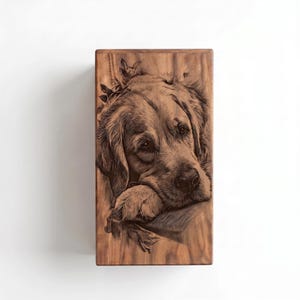 May include: A rectangular wooden plaque featuring a detailed, dark brown laser-engraved portrait of a golden retriever dog. The dog is depicted with its head resting on its paw, surrounded by subtle leaf accents, set against a natural wood grain.