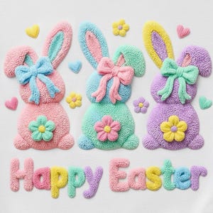 Könnte beinhalten: Weißes Sweatshirt mit drei gestickten Hasenmotiven in Pastelltönen: Rosa, Blau und Lila. Jeder Hase hat eine Schleife und eine Blume. Die Worte "Happy Easter" sind darunter in bunten Buchstaben gestickt. Herzen und Blumen schmücken das Design.