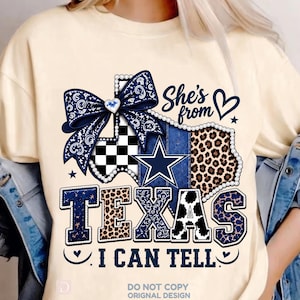 May include: A cream-coloured t-shirt featuring a graphic of the state of Texas decorated with a blue bandana-print bow, a black and white checkerboard pattern, a blue star, and leopard print. The text reads She's from TEXAS I CAN TELL.
