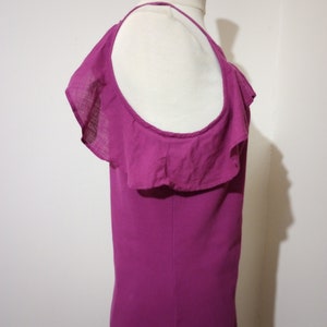 May include: A magenta sleeveless top with a ruffled neckline and a single strap. The top is made of a soft, lightweight fabric.