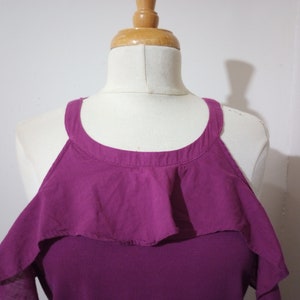 May include: A purple cold shoulder top with a ruffled neckline.