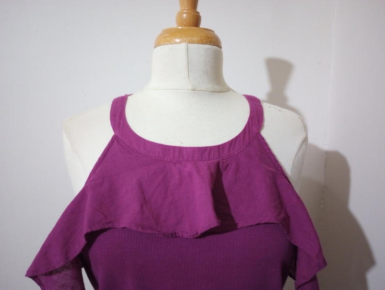 May include: A purple cold shoulder top with a ruffled neckline.