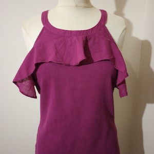 May include: A magenta sleeveless top with a ruffled neckline and short sleeves. The top is made of a soft, stretchy fabric.