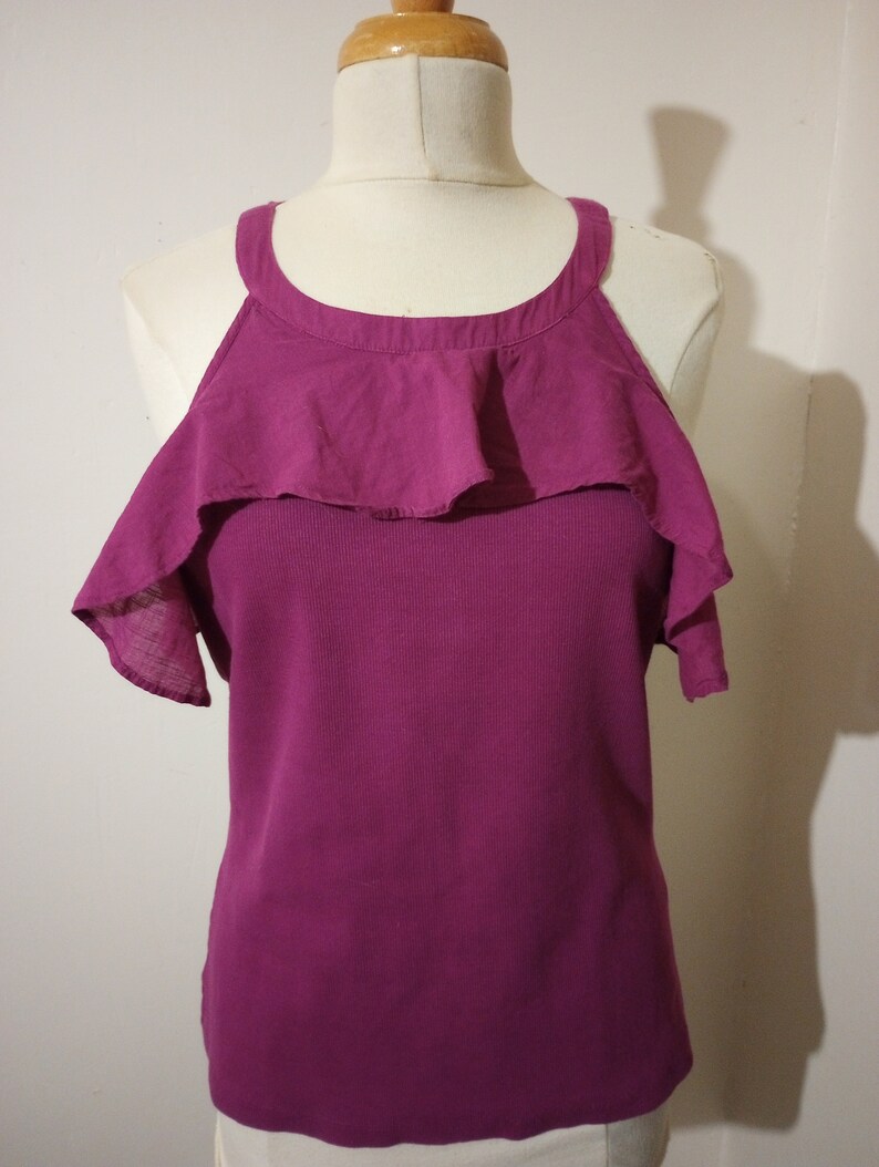 May include: A magenta sleeveless top with a ruffled neckline and short sleeves. The top is made of a soft, stretchy fabric.