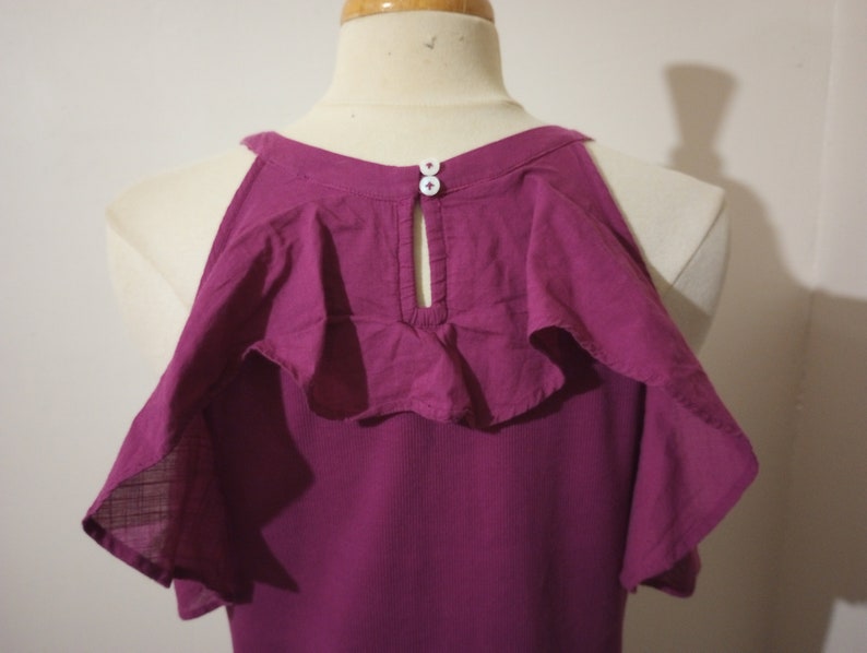 May include: A magenta cold shoulder top with ruffled sleeves and a button detail at the back of the neck.