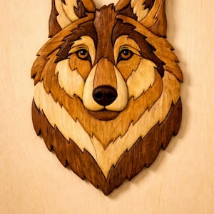 Peut inclure: Décoration murale en bois représentant une tête de loup. L'œuvre présente une sculpture détaillée du visage d'un loup, avec des nuances de bois brun et beige. Le loup a un nez brun foncé et des yeux couleur ambre. L'ensemble est monté sur un fond en bois clair.