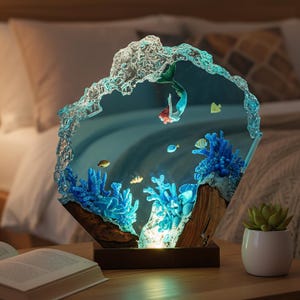 May include: A decorative lamp featuring a mermaid swimming in an underwater scene. The lamp has a blue and clear resin design with blue coral and fish. The base is a dark brown wood.