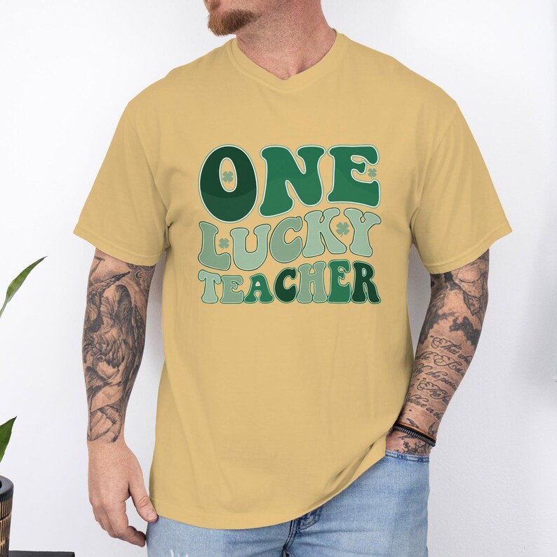 Mustard yellow Comfort Colors 1717 t-shirt for men featuring "One Lucky Teacher" typography. Vintage-inspired shamrock shirt, ideal for elementary or high school teachers.