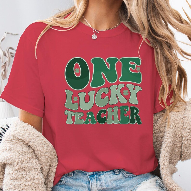 Red Comfort Colors 1717 shirt for teachers. "One Lucky Teacher" design in contrasting greens, trendy vintage holiday shirt for educators, modeled with a cream cardigan.