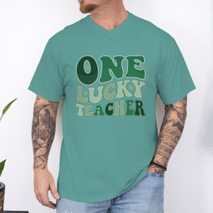 Comfort Colors 1717 Seafoam shirt on a male model. "One Lucky Teacher" groovy green letters, high-quality garment-dyed cotton tee for St. Patrick's Day school events.