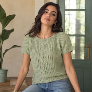 Peut inclure: Un haut en tricot vert sauge à manches courtes avec un motif de torsade verticale au centre, une encolure ronde et un point côtelé texturé sur tout le corps. Le vêtement est confectionné avec un fil léger et présente une coupe ajustée.