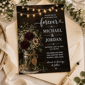 May include: A wedding invitation card featuring a dark wood background with string lights, a mason jar filled with dark red dahlias and baby's breath, and text reading: Please join us as we begin our forever, Michael & Jordan, July 19, 2025.