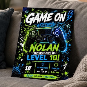 May include: A rectangular party invitation card featuring a black background with neon green and blue paint splatters, a video game controller graphic, and the text GAME ON LEVEL UP! NOLAN HAS REACHED LEVEL 10! with event details including date, time, and RSVP.