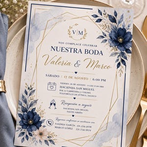 May include: A rectangular wedding invitation card featuring navy blue floral illustrations, gold geometric line accents, and a monogram with the letters V and M. The text includes the names Valeria and Marco, event details, and contact information.