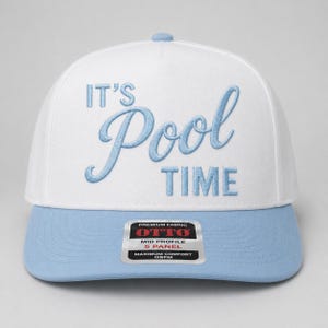 Könnte beinhalten: Eine weiße Baseballkappe mit fünf Paneelen, einem hellblauen Schirm und hellblau gesticktem Text auf der Vorderseite, der IT'S Pool TIME lautet. Ein rechteckiger Aufkleber auf dem Schirm zeigt den Text PREMIUM FABRIC OTTO MID PROFILE 5 PANEL.