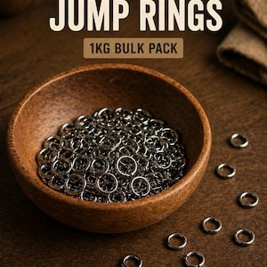 Puede incluir: Un cuenco de madera lleno de anillas de cadena plateadas y brillantes. El texto "CHAINMAIL JUMP RINGS" y "1KG BULK PACK" se muestra encima del cuenco. Varias anillas están esparcidas sobre una superficie de madera.