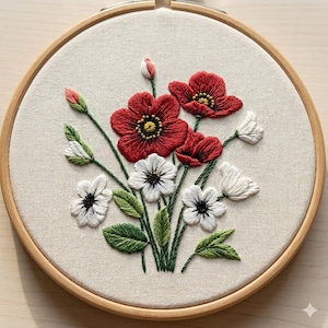 Puede incluir: Bordado floral hecho a mano con amapolas rojas y flores blancas con hojas verdes en un bastidor de madera. Las amapolas tienen centros amarillos, y las flores blancas tienen centros negros. La tela es de color beige claro. El diámetro es de unos 20 cm.