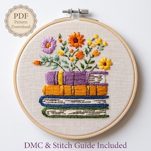 May include: A circular wooden embroidery hoop containing a fabric panel with a hand-stitched design of a stack of four books in purple, orange, blue, and green, topped with a bouquet of purple, orange, and yellow flowers. Text reads PDF Pattern Download.