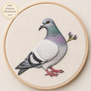 May include: A circular wooden embroidery hoop containing a fabric panel with a detailed thread-stitched pigeon. The bird features grey, white, and iridescent purple-green neck feathers, pink feet, and a small sprig of purple flowers. Text reads PDF Pattern Download.