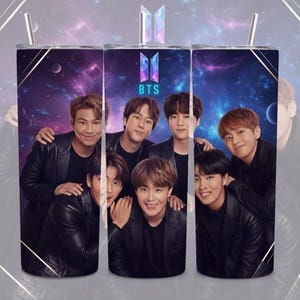 May include: A stainless steel tumbler featuring a group of seven people in black jackets against a space-themed background. The tumbler has a straw and the letters "BTS" with a logo.
