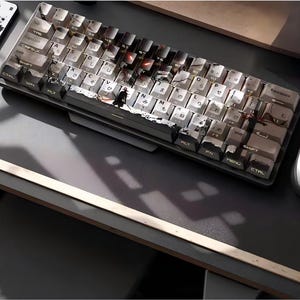 May include: A mechanical keyboard with white and black keycaps. The keycaps have Japanese characters and English letters. The keyboard has a black and silver frame. The keyboard is on a gray surface.