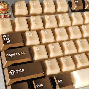 May include: Close-up of a mechanical keyboard with beige and brown keycaps. The keys are arranged in a standard QWERTY layout, with function keys and modifier keys visible. The keycaps have white lettering and symbols.