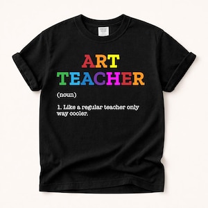 Puede incluir: Camiseta negra con la frase "ART TEACHER" en letras de colores. Debajo, una definición humorística: "Como un profesor normal, pero mucho más guay."