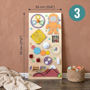 Pu&ograve; includere: Una tavola attivit&agrave; in legno, alta 70 cm e larga 35 cm, con elementi interattivi. Include ingranaggi, un labirinto, una figura di astronauta, un orologio e altri componenti colorati. La tavola &egrave; progettata per il gioco e l'apprendimento dei bambini.
