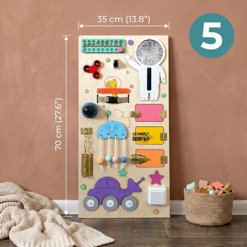Pu&ograve; includere: Una tavola di attivit&agrave; in legno, alta 70 cm e larga 35 cm, con vari elementi interattivi per bambini. Include uno spinner, chiusure, un interruttore e un'auto giocattolo. La tavola ha il numero 5.