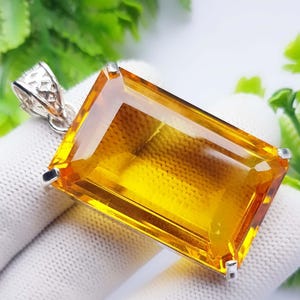 Può includere: Un ciondolo rettangolare in citrino giallo sfaccettato, montato su una struttura in metallo argentato con griffe. Il ciondolo presenta una pietra giallo oro vivace e trasparente con finitura lucida e un gancio argentato testurizzato.