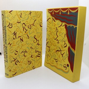 May include: Two yellow books with a repeating pattern of various letters in brown and light blue. The spine of the left book reads Edward Lear's Complete Nonsense. The right book features a stylized red and blue curtain graphic at the top.
