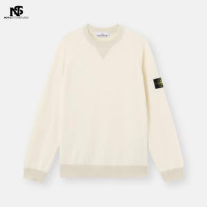 Op de afbeelding: Crèmekleurige trui met een ronde hals en lange mouwen. Voorzien van een kleine logopatch op de linkermouw en geribbelde details aan de hals, manchetten en zoom. De trui heeft een klassiek ontwerp.